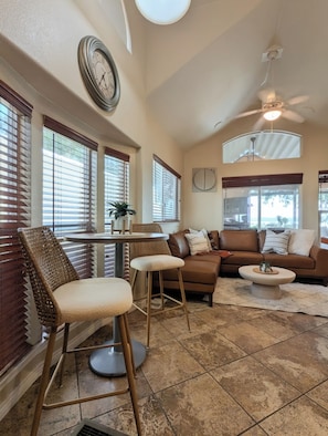 A spacious living area with a brown leather sofa, a round coffee table, and a wicker chair. - Lakefront Home — Marina & Sunset Views! (Lake Havasu City)