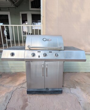Ein Grill aus Edelstahl mit vier Brennern, einer Seitablage und einer Bedienblende.