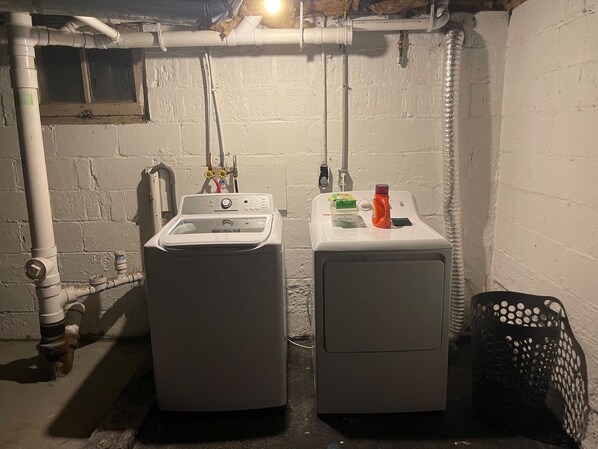 Zona de lavandería con dos lavadoras, un lavabo y diversos productos de limpieza.