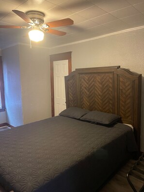 A bedroom with a bed, a ceiling fan, and a door.