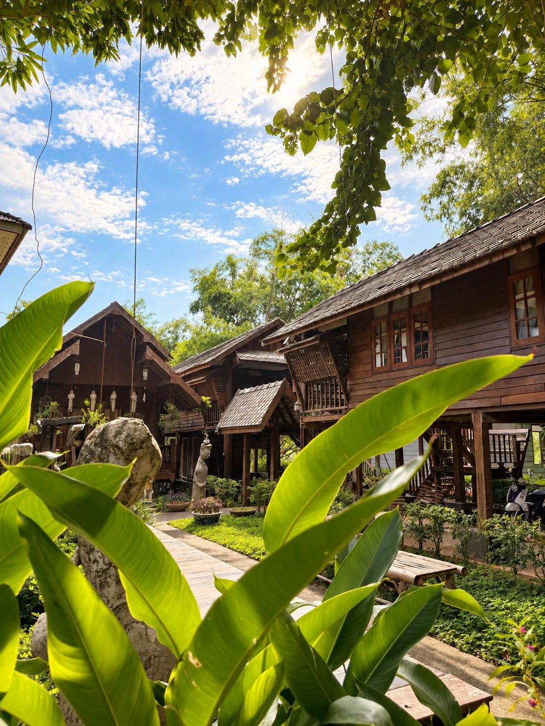 A traditional wooden building with a covered patio area, surrounded by lush greenery and a clear sky.