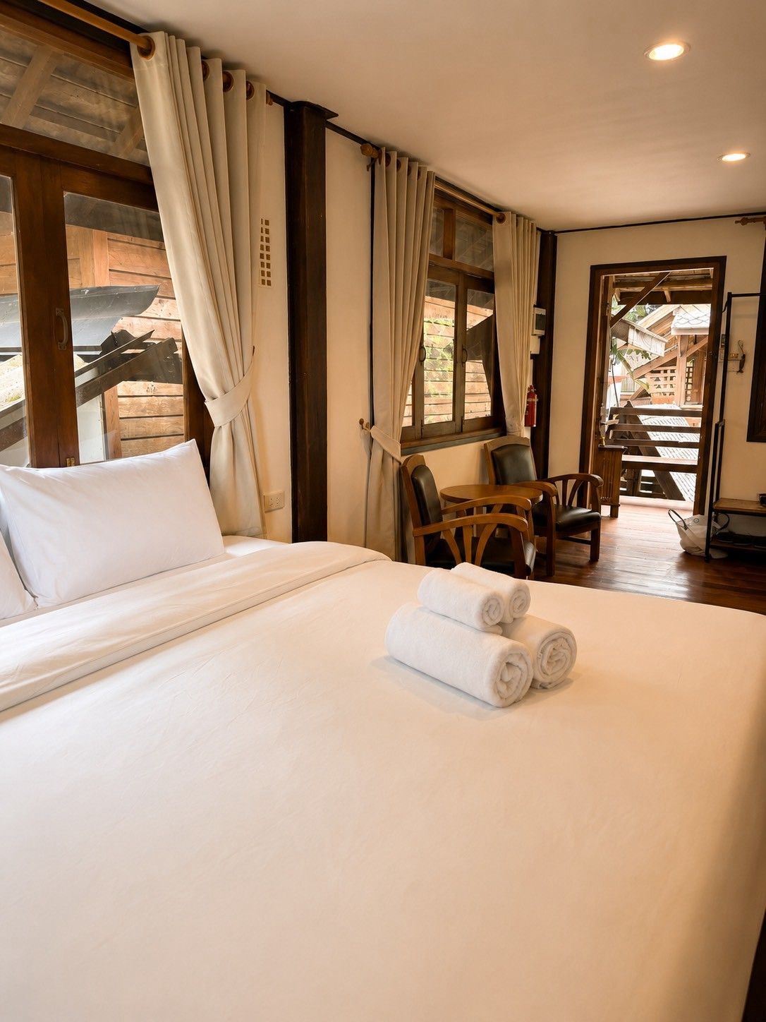 Een hotelkamer met een groot bed, een eettafel en stoelen.