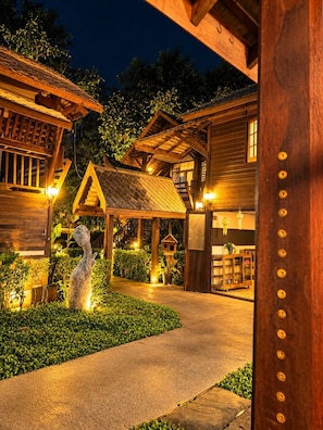 A wooden cabin with a stone statue, a covered walkway, and a small garden. - Chaba Varee Resort Doi Saket Chiang Mai (Pa Meung)