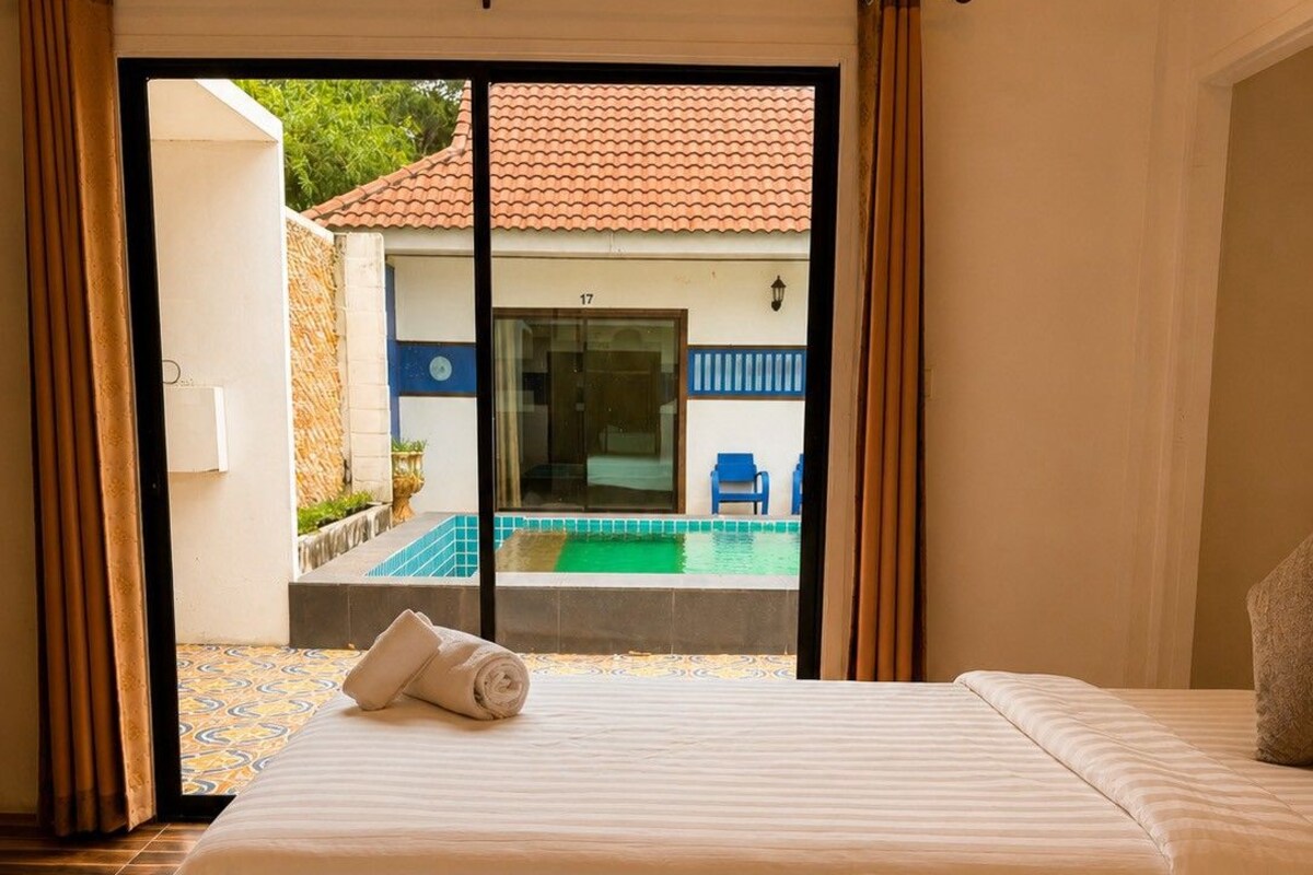 A hotel room with two beds, a view of a pool, and a balcony with a door.
