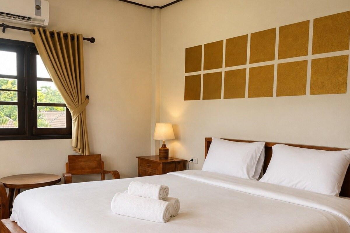A hotel room with a large bed, a bedside table, a lamp, and a window with curtains.