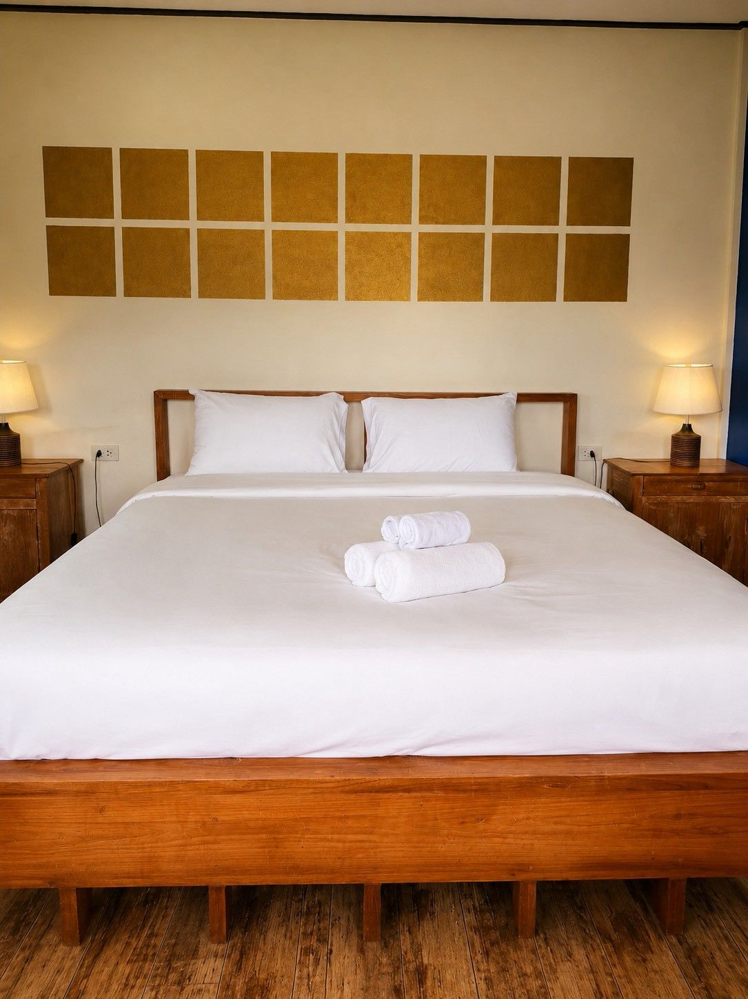 A hotel room with a large bed, two bedside tables, and a wall with a geometric pattern.