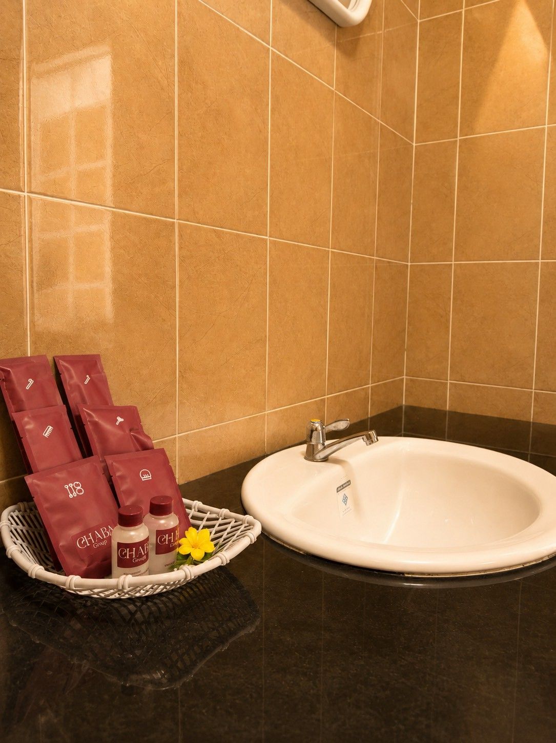 Et badeværelse med en hvid vask, en kurv med toiletartikler og en håndklædestang.