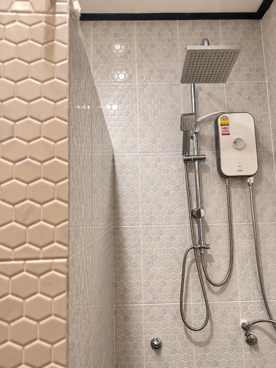 A shower with a square head, a handheld showerhead, and a wall-mounted control unit.