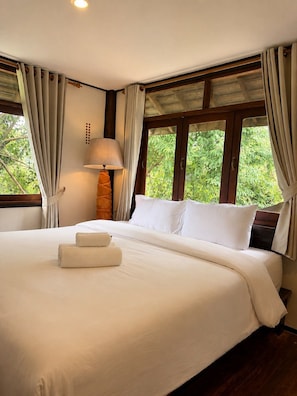 A hotel room with a large bed, a bedside lamp, and a window with curtains. - Chaba Varee Resort Doi Saket Chiang Mai (Pa Meung)