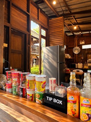 Uma cozinha com geladeira, um recipiente para gorjetas e diversos alimentos sobre o balcão.