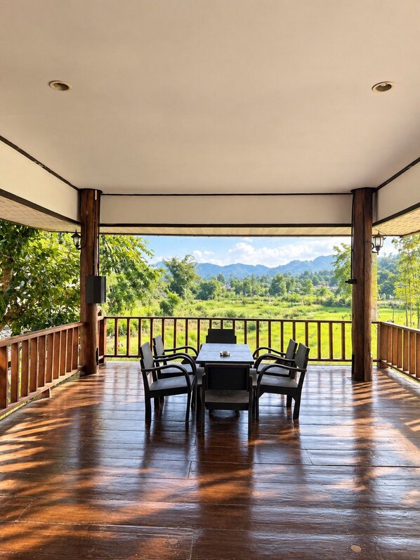 A covered outdoor seating area with a table and chairs, overlooking a lush landscape with mountains. - Chaba Varee Resort Doi Saket Chiang Mai (Pa Meung)