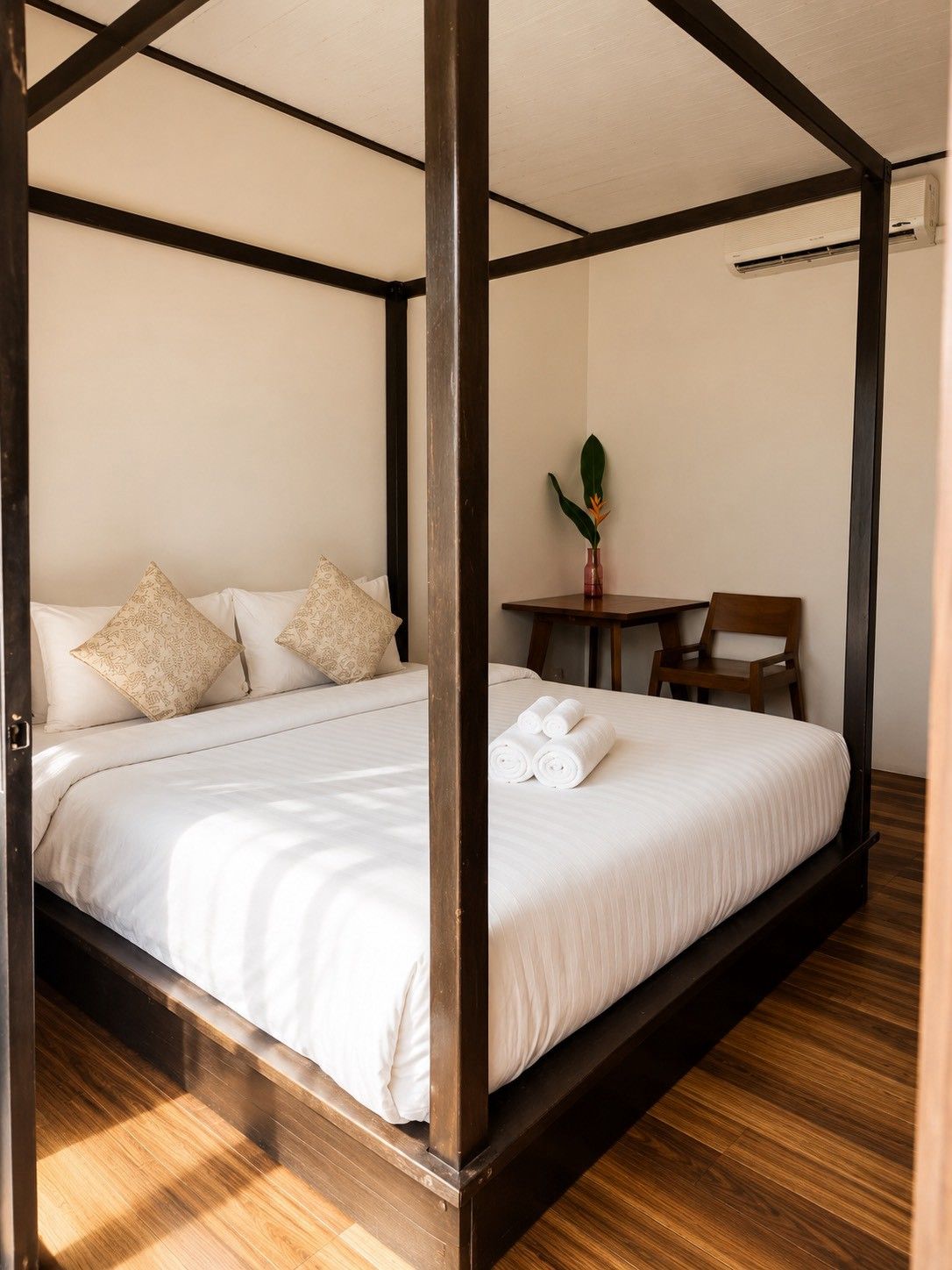 A four-poster bed with a wooden frame, white linens, and patterned pillows.