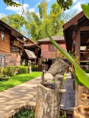 A rustic wooden building with a stone pathway leading to a wooden structure resembling a well.