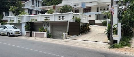 A residential building with a gated entrance, a driveway, and a parked car.