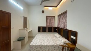 Quarto com cama, mesa de cabeceira, guarda-roupa e ventoinha no teto.