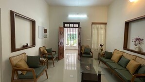 Uma sala de estar bem iluminada com uma mesa de centro de vidro, dois sofás e uma mesa de jantar.