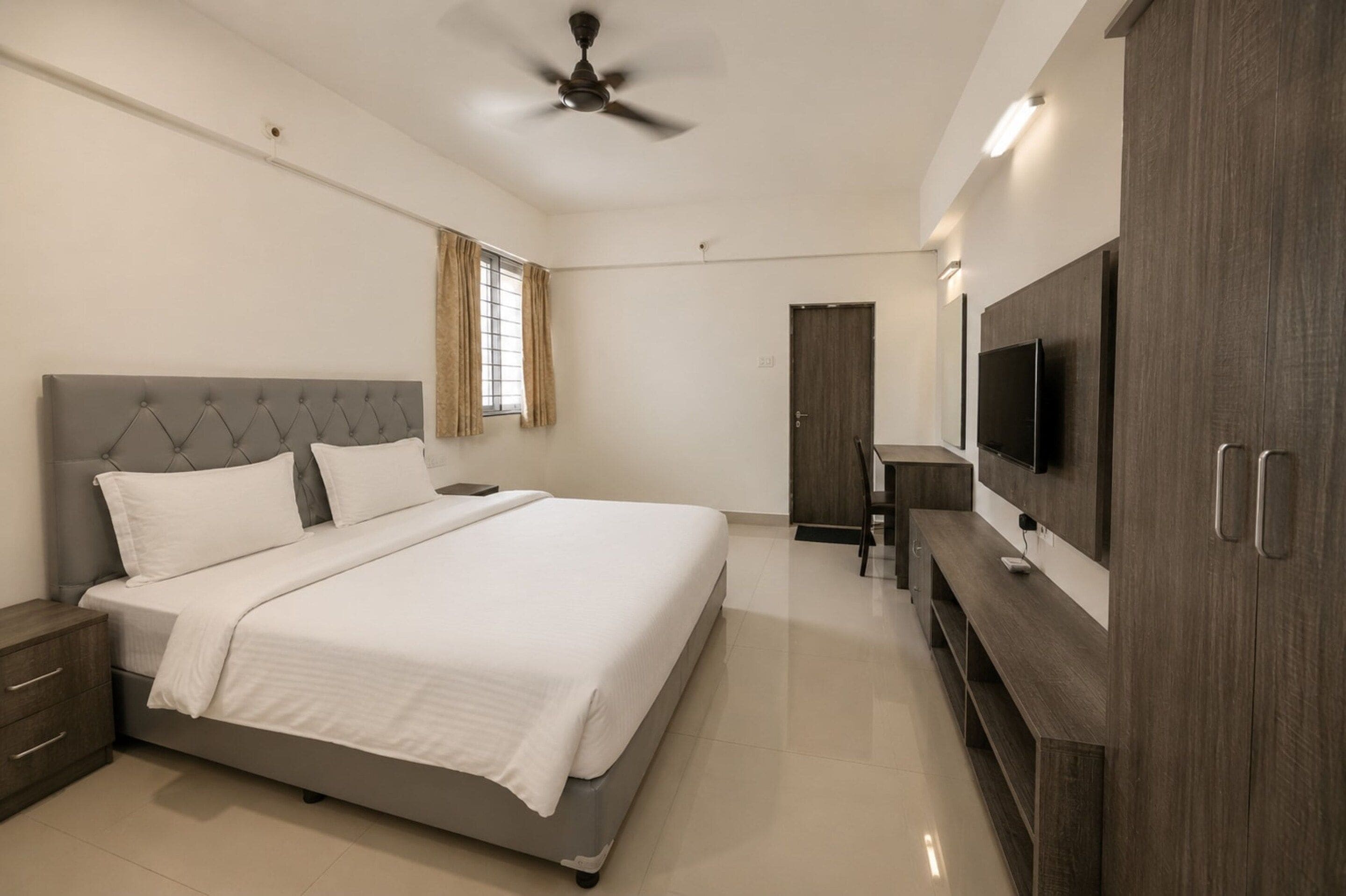 Un dormitorio moderno con cama, mesitas de noche, televisión y armario.
