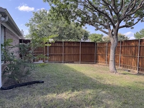 A backyard with a wooden fence, a tree, and a building.