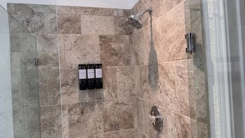 A shower area with a glass door, a handheld showerhead, and a wall-mounted control panel.