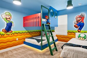 Ein Schlafzimmer mit einem Bett, einer Leiter und Wanddekorationen, darunter Figuren aus Mario.