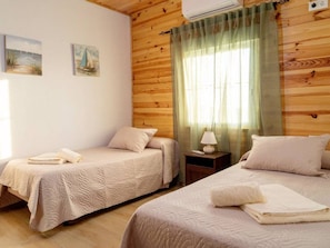 Habitació amb dos llits, una tauleta de nit amb una làmpada i una finestra amb cortines.