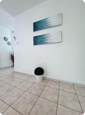 Ein Flur mit gefliestem Boden und zwei an der Wand befestigten Kunstwerken.