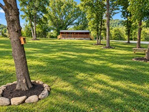 A wooden cabin with a balcony, surrounded by a well-maintained grassy area and trees.