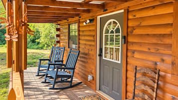 Une cabane en bois avec une véranda, des fauteuils à bascule et une porte dotée d’une fenêtre.