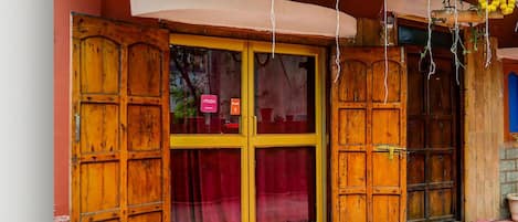 A wooden door with a red curtain, a white awning, and a yellow flower garland.