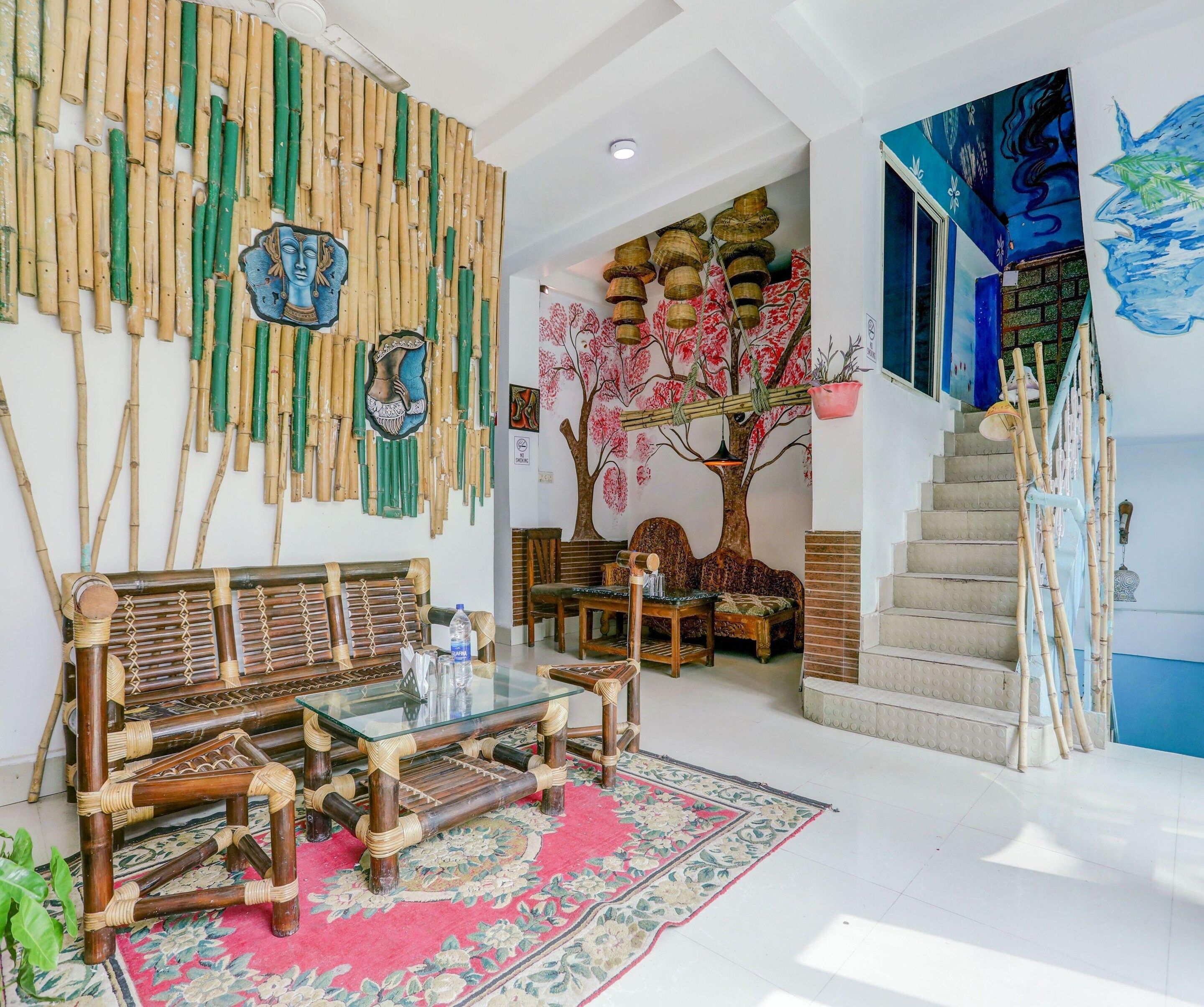 A room with a traditional bamboo wall, a sofa set, a glass coffee table, a staircase, and a painting.