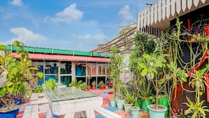 Une cour avec un banc en bois, des plantes en pot et un bâtiment doté d’un toit en tuiles.