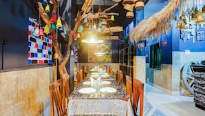 Un restaurant doté d’une longue table à manger, de chaises en bois et d’éléments décoratifs suspendus.