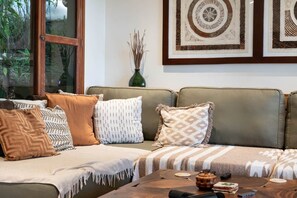 Ein Wohnzimmer mit einer Couch, Kissen, einem Couchtisch und gerahmten Kunstwerken an der Wand.