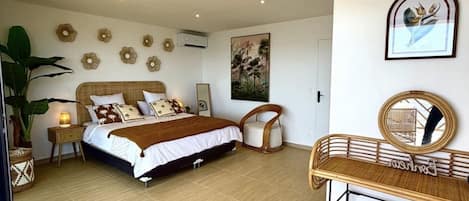 Un dormitorio con cama, mesitas de noche, una silla, escritorio y espejo.