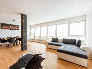 A modern living room with a dining area, large windows, and a stone pillar. - Chalet in Stuhlfelden Near Ski Slopes (Stuhlfelden)