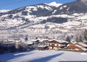 Ein verschneites Bergdorf mit traditionellen Holzhäusern und freiem Blick auf die umliegenden Berge.