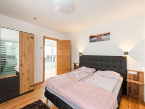 A bedroom with a bed, wooden wardrobe, and a door leading to a balcony. - Chalet in Stuhlfelden Near Ski Slopes (Stuhlfelden)