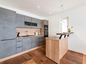 Uma cozinha moderna com armários cinza, bancada de madeira e forno embutido.