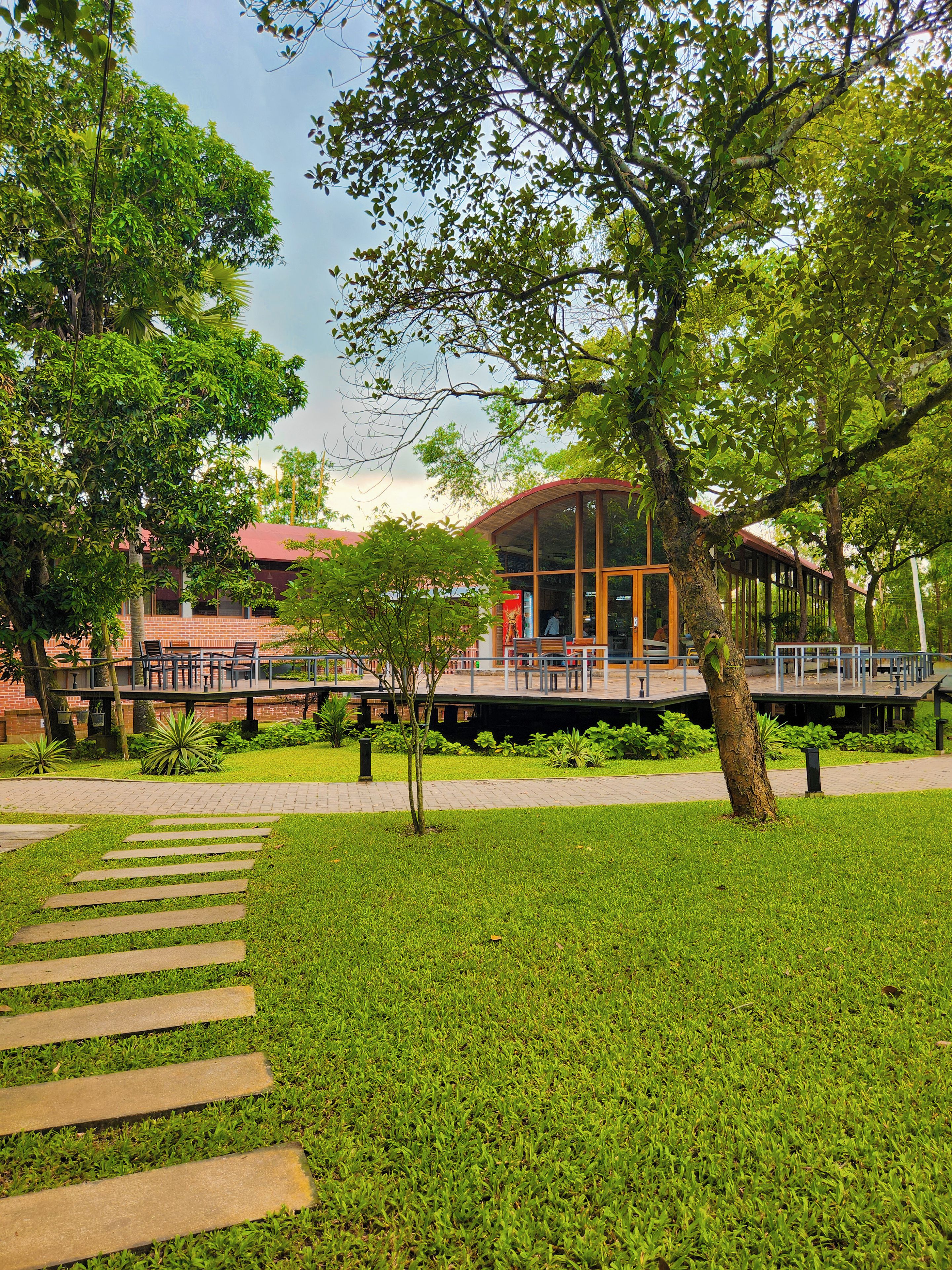 A building with a glass facade, surrounded by a well-maintained lawn and a paved walkway.