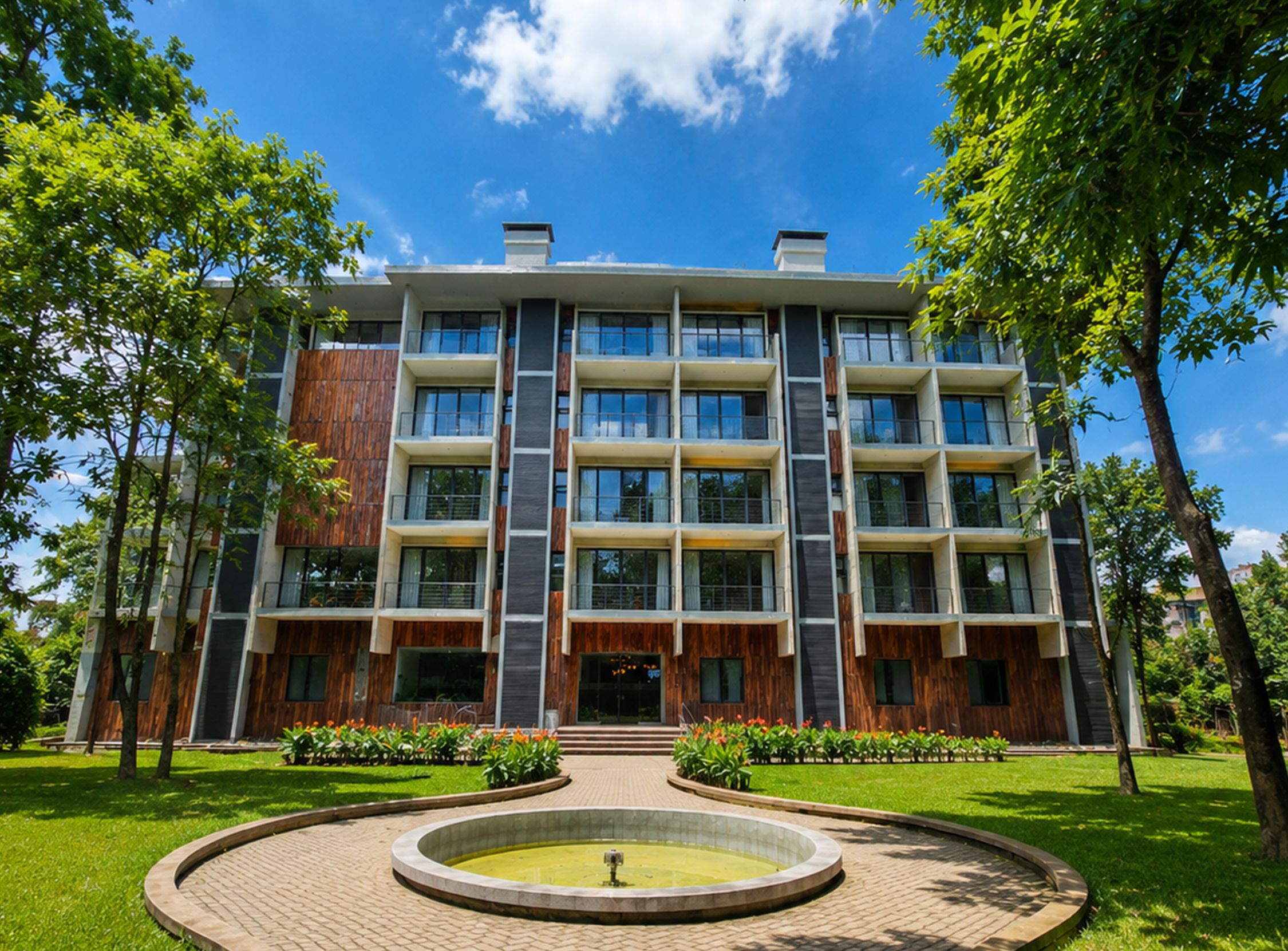 A multi-story building with a central courtyard, surrounded by trees and a well-maintained lawn.