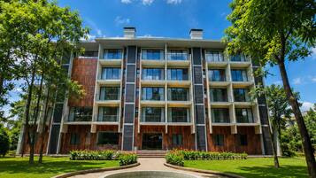 A multi-story building with a central courtyard, surrounded by trees and a well-maintained lawn.