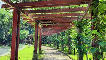 A wooden pergola structure with a gravel pathway leading through it, surrounded by greenery.