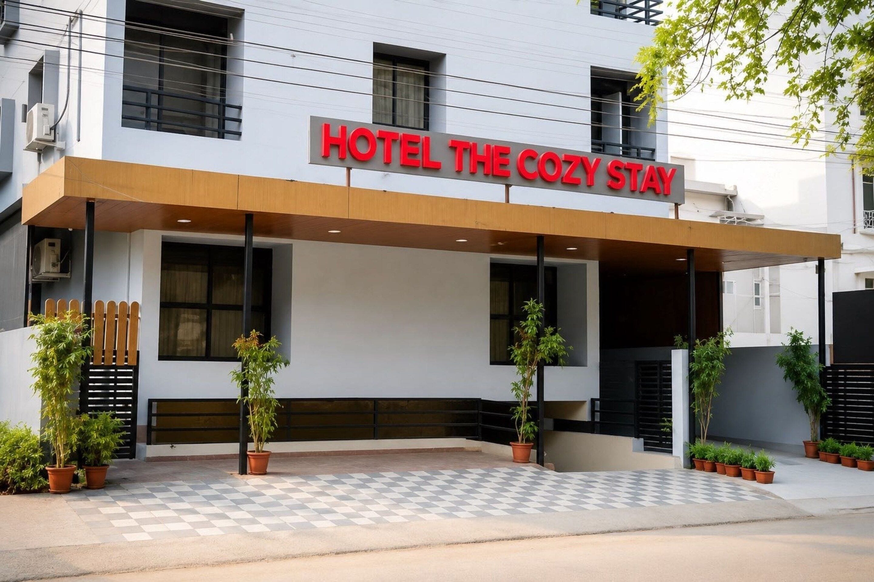 Entrada de un hotel con un letrero que dice 'HOTEL THE COZY STAY'.