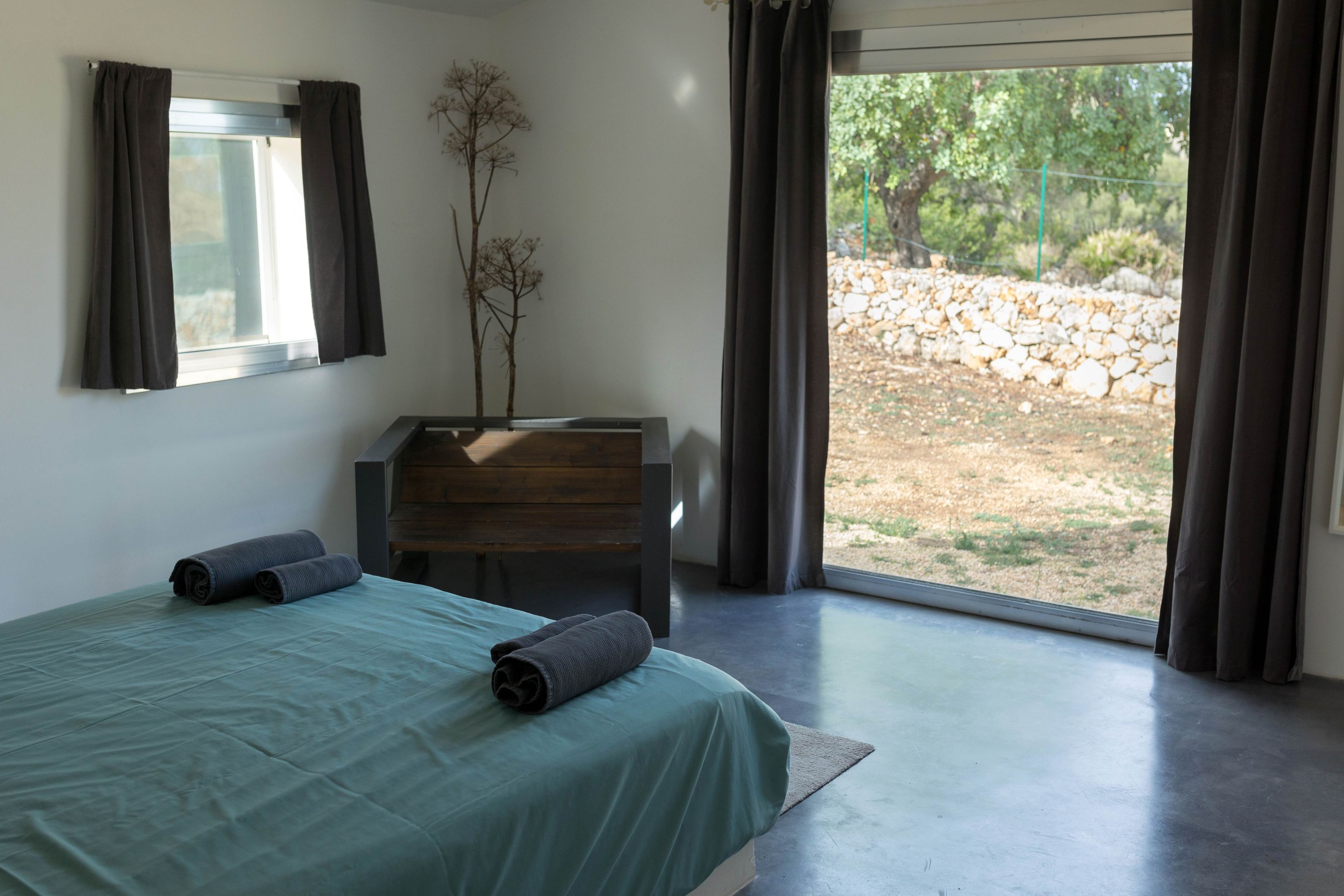 Ein Schlafzimmer mit Bett, Schminktisch, Spiegel und Blick ins Freie.