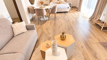 A modern living room with a sofa, coffee table, and a dining area with chairs and a table.