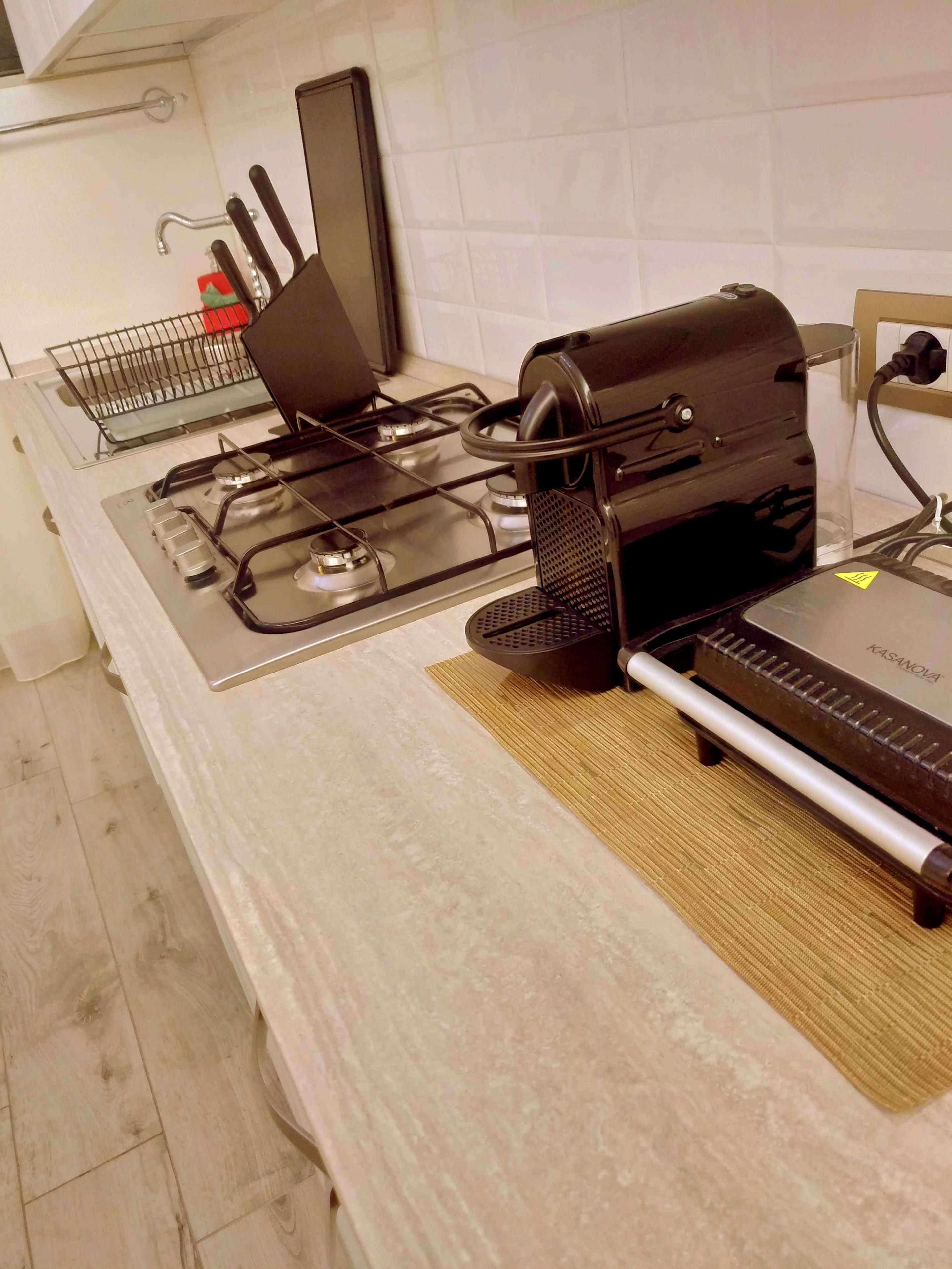 Une cuisine équipée d’une cuisinière à gaz, d’une machine à café et d’une bouilloire posées sur le plan de travail.