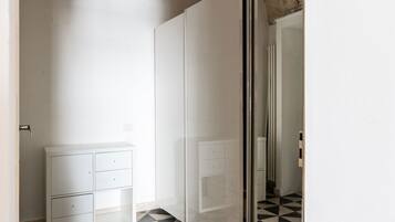 Un couloir étroit avec une armoire blanche et une porte vitrée donnant sur une autre pièce.