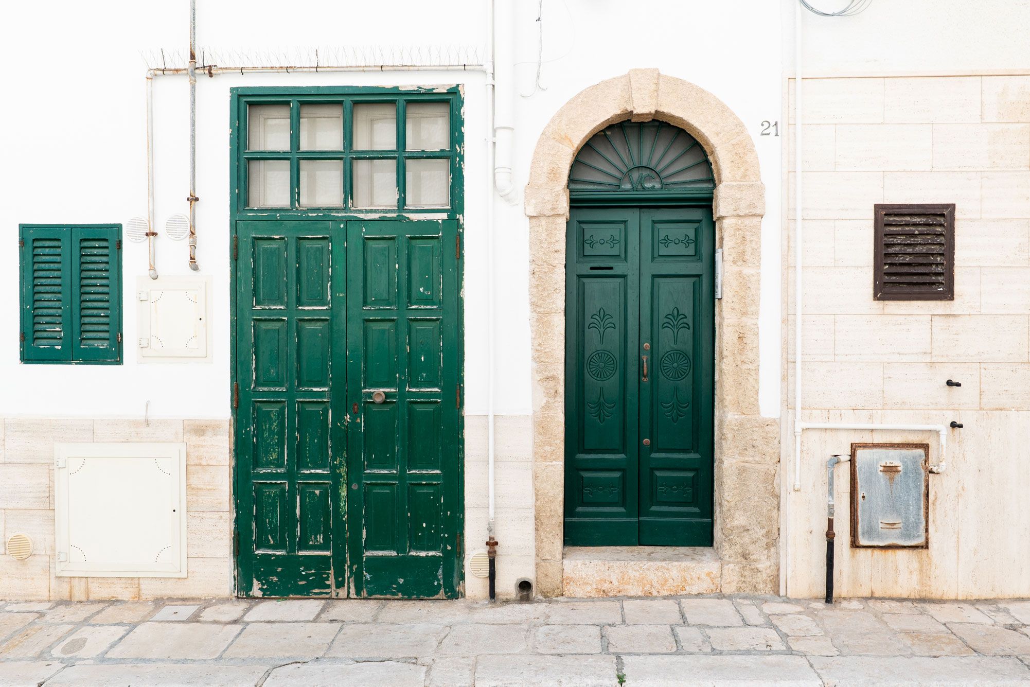 Un bâtiment avec une porte verte, une arche en pierre et une plaque commémorative sur le mur.