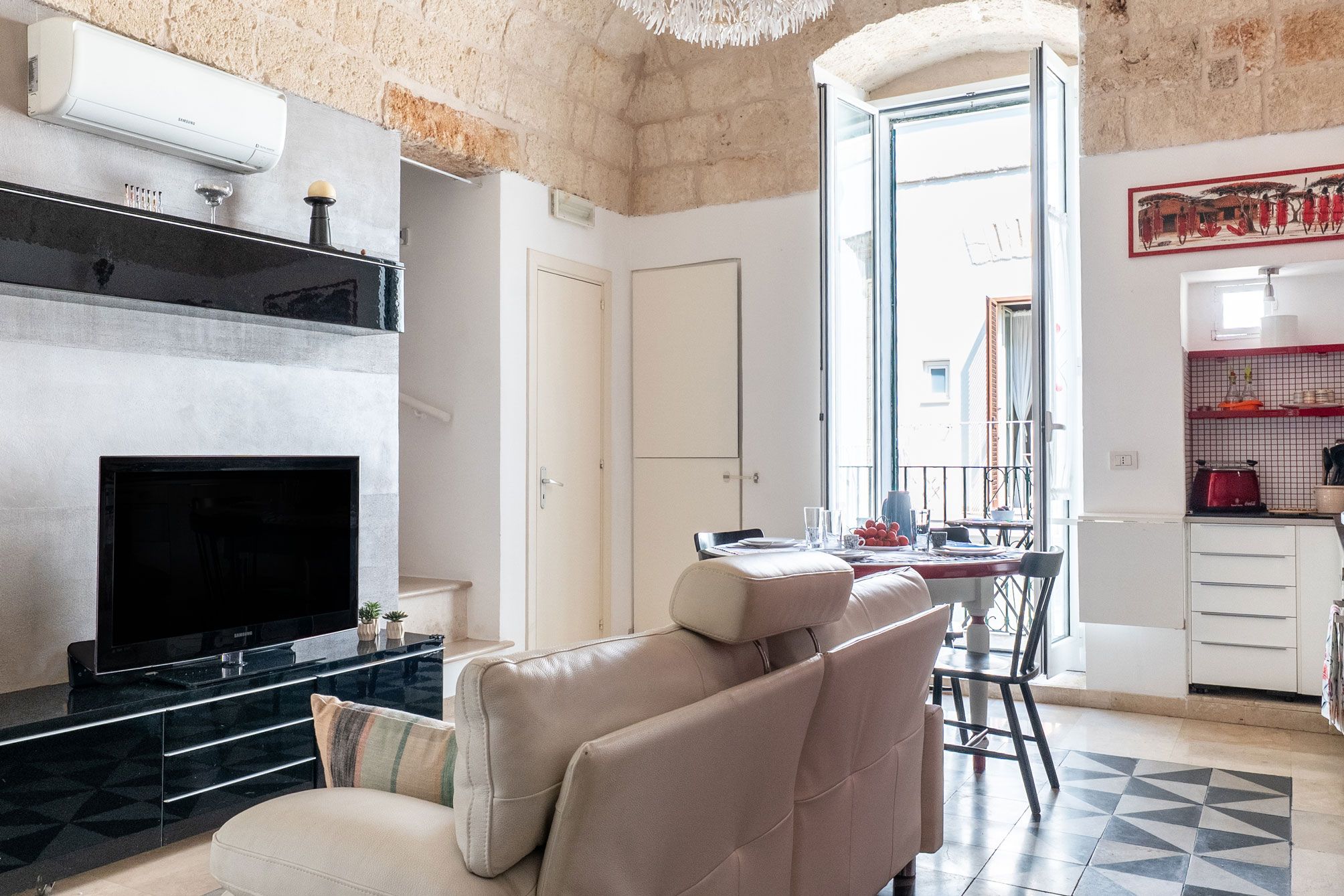 Un salon avec une cheminée, un canapé, un coin repas et une cuisine.