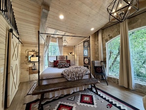 Ein Himmelbett mit Baldachin, eine Steinwand und ein großes Fenster mit Vorhängen.